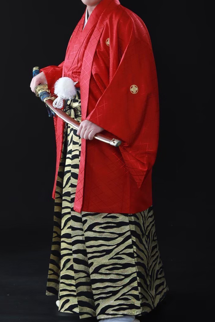 赤の着物とゴールドの袴を着ている男性