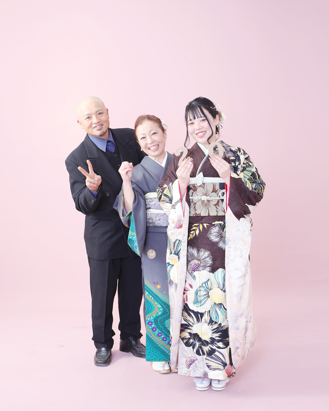 振袖を着た20歳の女の子と、お父さんお母さんの3人の家族写真