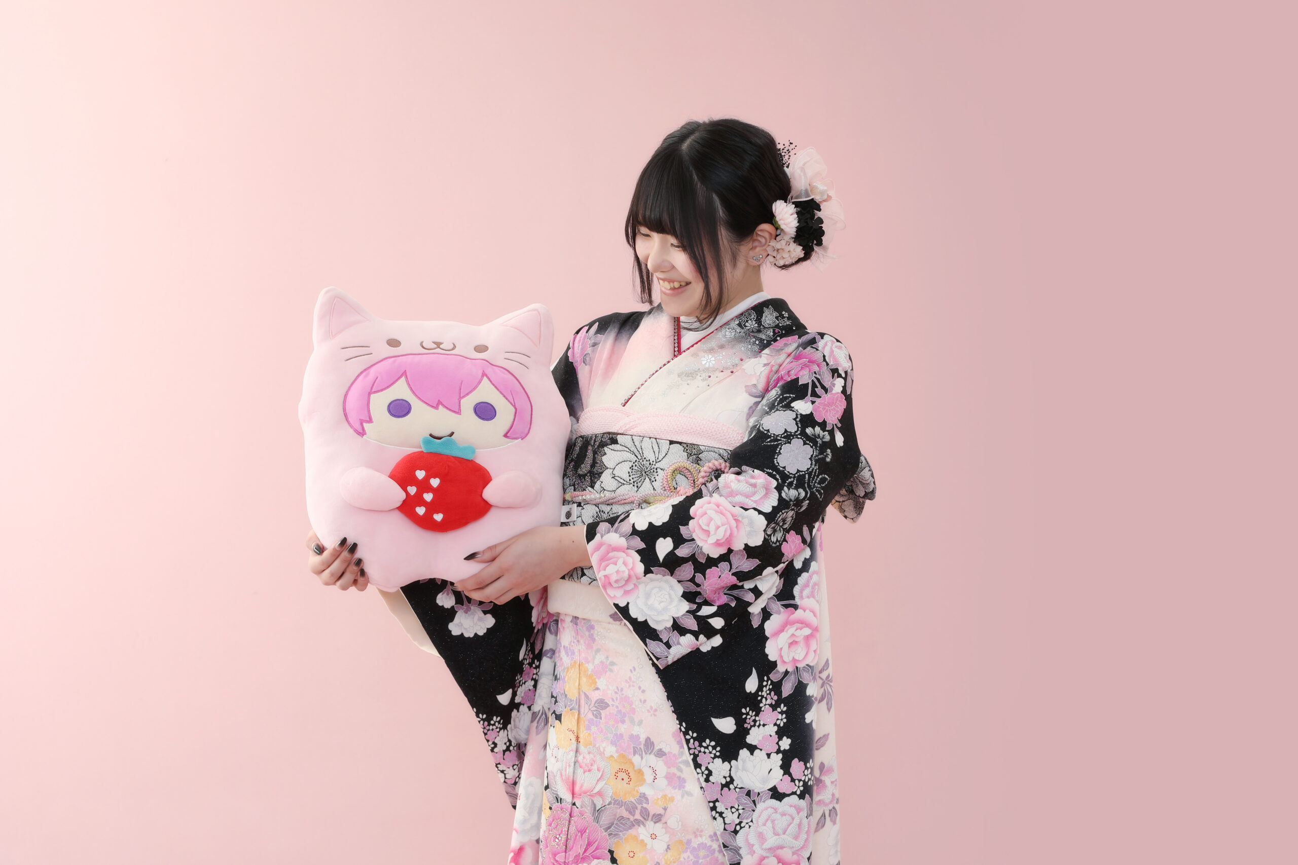 黒色の振袖を着て、ピンク色の推しのぬいぐるみを持っている20歳の後撮りの女の子